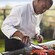 Un chef usa pinzas para revisar las colas de langosta que se asan en una parrilla al aire libre